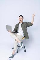 jung asiatisch Geschäft Mann Sitzung auf Stuhl und mit Laptop auf Hintergrund foto