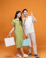 jung asiatisch Paar halten Einkaufen Tasche auf Hintergrund foto
