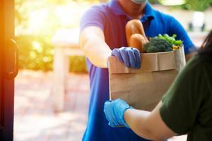 Foodservice-Anbieter mit Masken und Handschuhen. Zu Hause bleiben reduziert die Ausbreitung des Covid-19-Virus foto