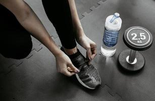 Frau, die ihre Schnürsenkel bindet. Nahaufnahme des weiblichen Sport-Fitness-Läufers, der sich zum Joggen im Fitnessstudio fertig macht foto