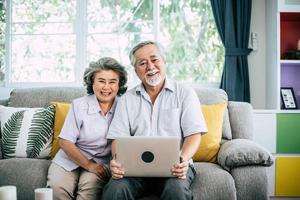 älteres Paar, das spricht und Laptop-Computer benutzt foto