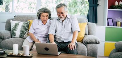 älteres Paar, das spricht und Laptop-Computer benutzt foto