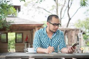 junger Geschäftsmann, der Smartphone während der Arbeit im Hausgarten verwendet