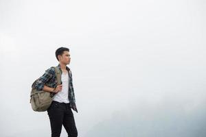 Wanderer mit Rucksack, der oben auf einem Berg steht und Naturblick genießt foto