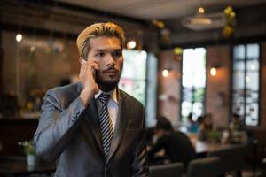 hübscher Geschäftsmann, der am Telefon spricht, während er eine Pause im Café macht