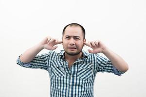 Porträt eines jungen unglücklichen, gestressten Mannes, der seine Ohren bedeckt foto