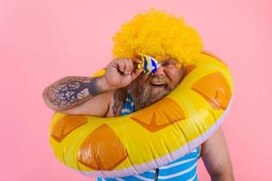 Fett Mann mit Perücke im Kopf ist bereit zu schwimmen mit ein Krapfen Lebensretter foto
