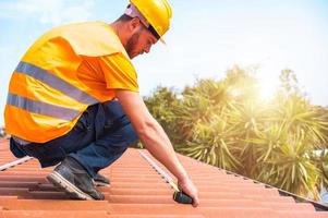 technisch Arbeiter nimmt Messungen auf das Dach von ein Haus foto