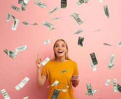 blond süß Mädchen Gewinnt Geld mit Smartphone App. erstaunt und überrascht Ausdruck Gesicht. Rosa Hintergrund foto