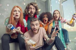 glücklich freunde von Fußball Fans Aufpassen Fußball auf Fernseher und feiern Sieg mit fallen Konfetti. foto