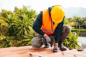 technisch Arbeiter funktioniert mit bohren auf das Dach von ein Haus foto