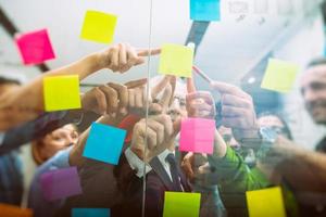 Mannschaft von Menschen beim Arbeit im das Büro zeigt an mit ihr Hand ein Klebstoff Hinweis auf das Glas foto