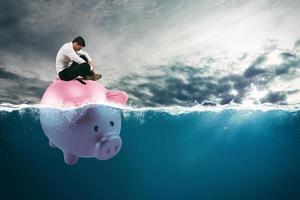 Geschäft Mann im finanziell Ärger Segel auf Schweinchen Bank im Schlecht Wasser fällig zu das Krise foto