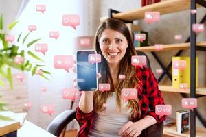 glücklich Frau zeigt an ihr Smartphone mit Sozial Netzwerk Mitteilungen, Plaudern und Benutzer Symbole foto