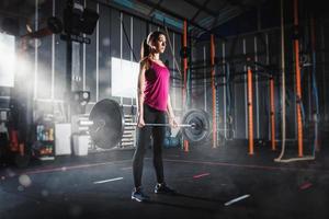 sportlich Mädchen funktioniert aus beim das Fitnessstudio mit ein Hantel foto