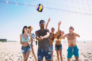 Gruppe von freunde spielen beim Strand Volley beim das Strand foto