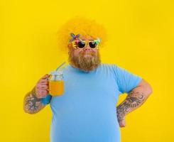 Fett glücklich Mann mit Perücke im Kopf und Sonnenbrille Getränke ein Obst Saft foto
