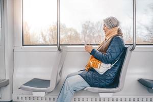 Senior Frau senden Botschaft mit ein Handy, Mobiltelefon Telefon im ein Zug foto