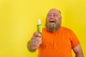 glücklich Mann mit Bart und Tätowierungen hält ein Hände Reiniger gegen covid19 foto