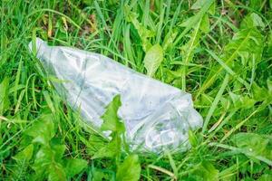 Zerknitterte Plastikflasche, die im grünen Gras liegt foto