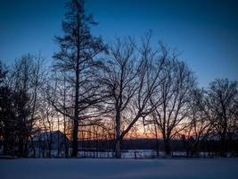 Baumreihe und eine Scheune mit einem bunten Sonnenaufgang in einem klaren blauen Himmel foto