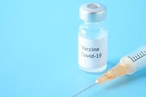 Impfstoff und Spritze auf blauem Hintergrund foto