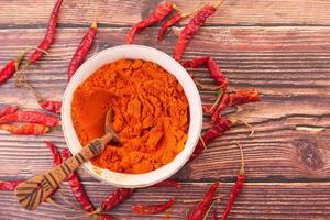 Chilipulver und getrocknete Paprika auf Tischhintergrund foto