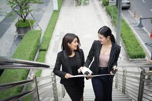 junge asiatische Geschäftsfrauen mit Dokumenten, die auf Treppen gehen foto