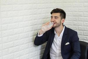 Trinkwasser des jungen Geschäftsmannes im Büro foto