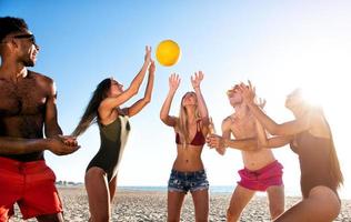 Gruppe von freunde spielen beim Strand Volley beim das Strand foto