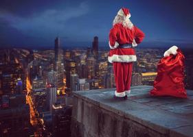 Santa claus sieht aus Nieder auf das Stadt warten zu liefern das die Geschenke foto