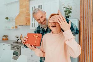 Mann gibt ein Geschenk zu ihr Ehefrau beim Zuhause foto