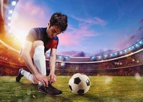 Fußball Spieler Bindungen seine Fußball Schuhe bereit zu abspielen beim das Stadion foto