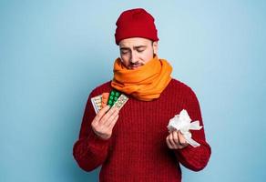 Junge gefangen ein kalt und Verwendet Tabletten zu heilen. Studio auf cyan Hintergrund foto