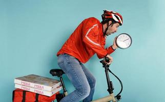 Lieferant läuft schnell mit elektrisch Fahrrad zu liefern Pizza und vermeiden verzögern foto