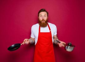 erstaunt Koch mit Bart und rot Schürze Köche mit schwenken und Topf foto