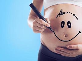 Smiley gezeichnet auf ein schwanger Frau Bauch foto