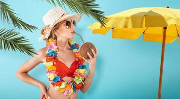 Frau mit Badeanzug erfrischend mit ein Kokosnuss foto