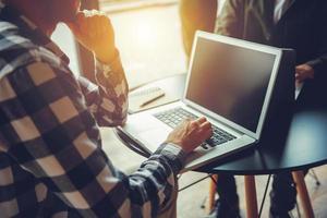 Geschäft Mann funktioniert mit Laptop auf ein Tabelle im ein modern Büro in der Nähe von Fenster foto