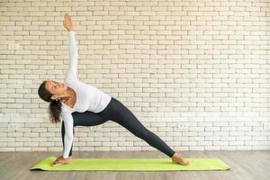 lateinische frau, die yoga auf matte praktiziert foto