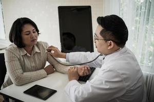 Arzt im Weiß Uniform Kleid Hör mal zu Lunge und Herz geduldig mit Stethoskop foto