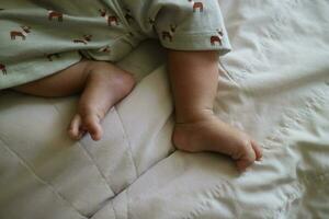 süß Füße von ein Neugeborene Baby auf ein Weiß Matratze foto