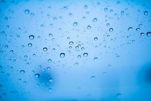 Blau Wasser Tröpfchen und Regentropfen haften zu das cool klar Glas foto