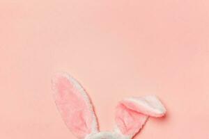 glücklich Ostern Konzept. dekorativ Hase Ohren pelzig Kostüm Spielzeug isoliert auf modisch Pastell- Rosa Hintergrund foto
