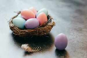 glücklich Ostern Konzept. Vorbereitung zum Urlaub. bunt Pastell- dekoriert Ostern Eier im Nest auf Grunge zerkratzt dunkel schwarz Schiefer Hintergrund. einfach Minimalismus Kopieren Raum. foto