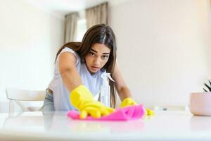 Schuss von ein jung Frau suchen müde während Reinigung beim heim. müde jung Frau Stehen mit Reinigung Produkte und Ausrüstung, Hausarbeit Konzept. foto