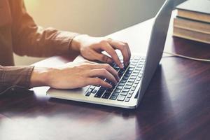 schließen oben Hand Geschäft Tippen Computer Laptop im das Büro mit Sonnenlicht. Jahrgang getönt Filter. foto