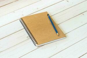 braun Notizbuch mit leer Seiten und Bleistift auf Holz Tabelle foto