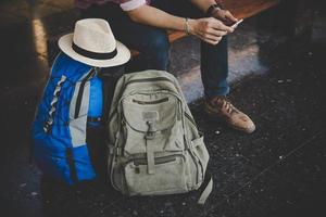 junger Hipster-Mann, der auf Bank am Bahnhof sitzt foto