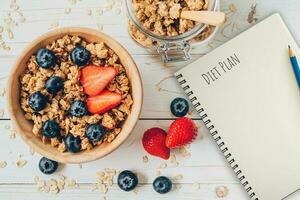 hausgemacht Granola und frisch Beeren auf Holz Tabelle mit Hinweis Buch und Text Diät planen Konzept, Kopieren Raum. foto